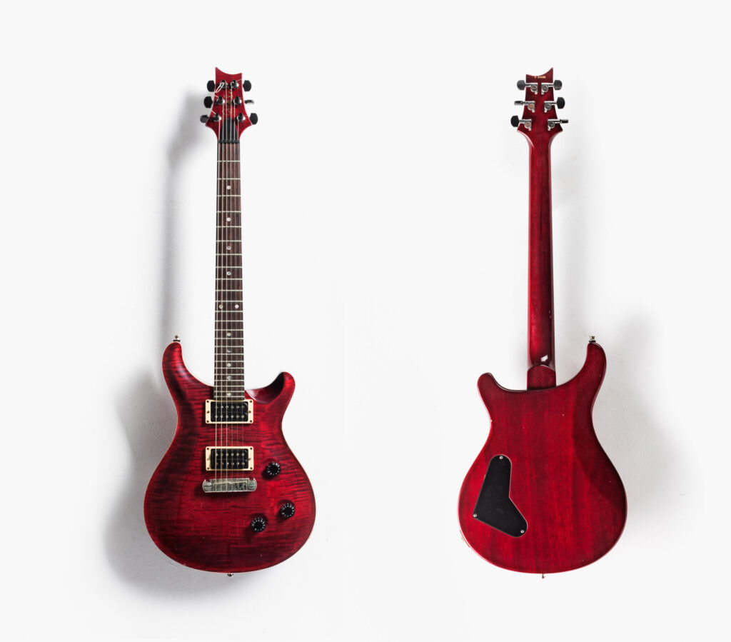 Front and back of guitar on white background with shadows.