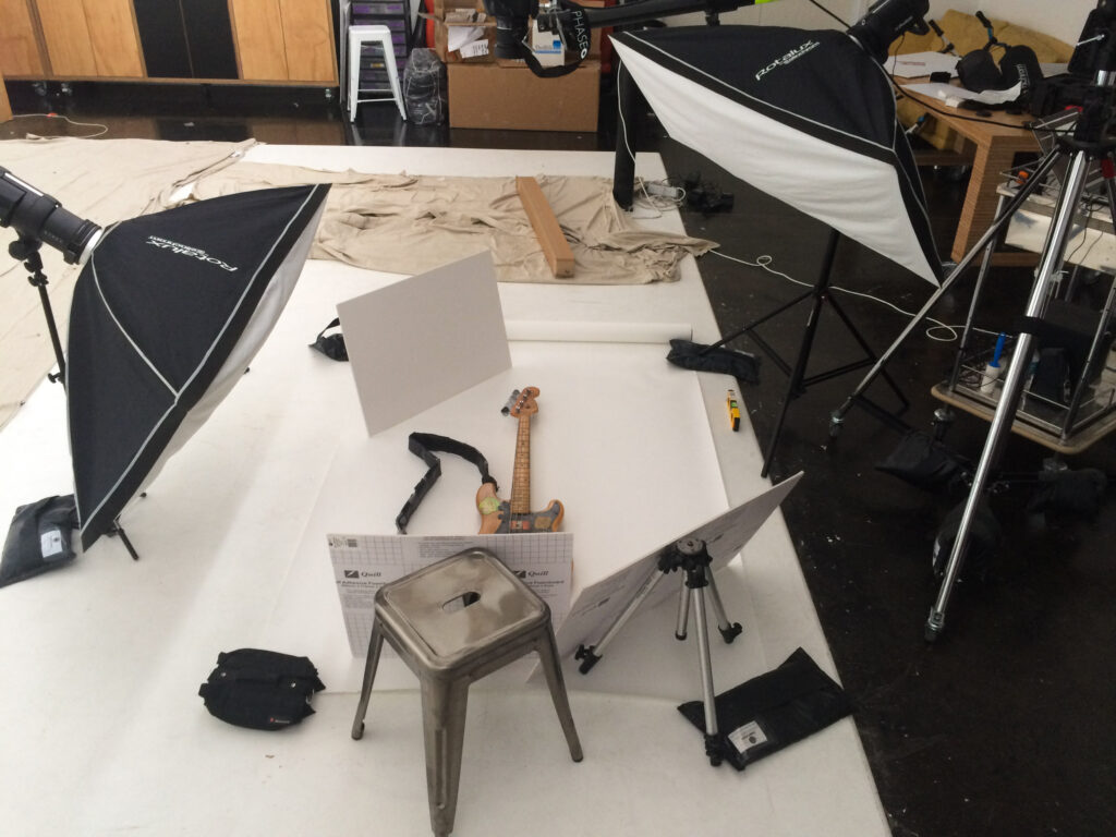 Photographic shoot set up with guitar on white floor and lights surrounding