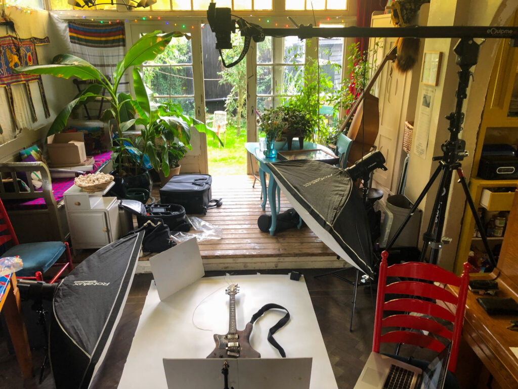 Photographic set up in room with indoor plants looking out over garden. Guitar at the front of the image.